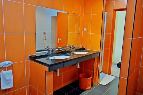 a bathroom with two sinks and an orange wall at Hotel Joffre in Toamasina