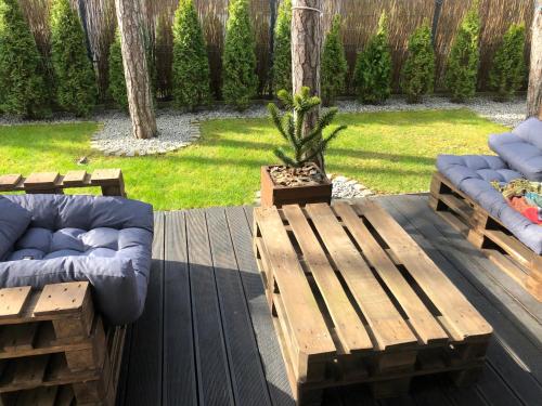 a wooden deck with two couches and a bench at Villa Ohana in Pobierowo 300 m from the beach in Pobierowo