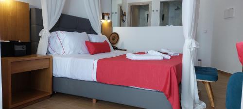 a bedroom with a bed with a red blanket and a mirror at Cavo Orient Beach Hotel & Suites in Tragaki