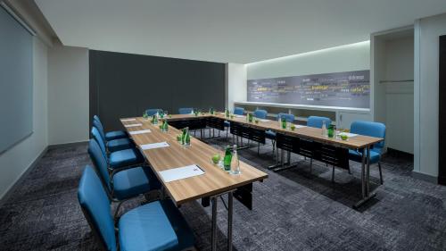 a conference room with wooden tables and blue chairs at Ibis Jeddah Malik Road in Jeddah