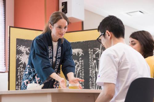 a woman standing at a counter talking to a man at Wild Cherry Blossom-HOSTEL,TOKYO KOGANEI- in Koganei