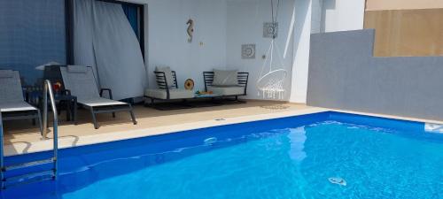a large blue swimming pool in a room with chairs at Cavo Orient Beach Hotel & Suites in Tragaki
