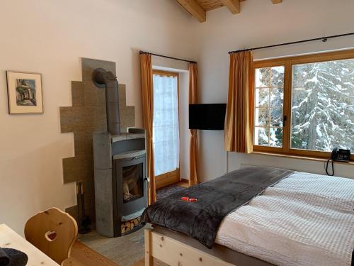 a bedroom with a bed and a fireplace in front of a window at Chasa al Battaporta in Tschierv