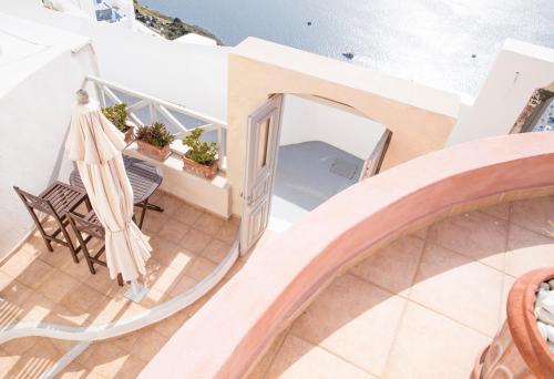 a spiral staircase leading to a balcony with a umbrella at Panorama Suites in Fira