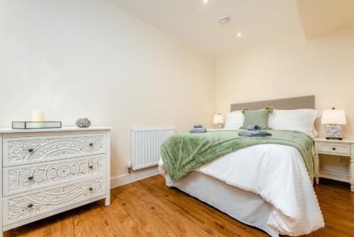 a white bedroom with a bed and a dresser at The Bear in Usk