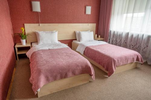 a hotel room with two beds and a window at Šiaurės Vartai in Joniškis