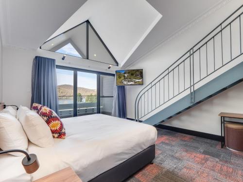 a bedroom with a bed and a staircase at Banjo Paterson Inn in Jindabyne