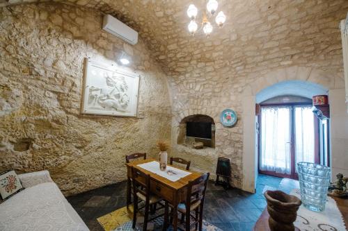 a living room with a table and a stone wall at Le Cacinare in Modica