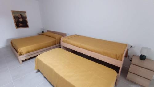 two beds in a room with yellow sheets at Rosa's Rooms in Matera