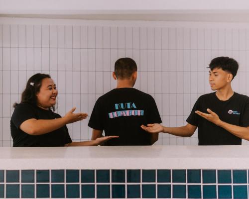 a woman and two men standing in a locker room at Mad Monkey Kuta Lombok in Kuta Lombok