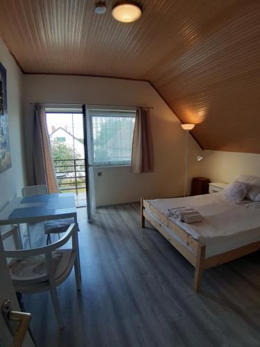 Schlafzimmer mit einem Bett, einem Tisch und einem Fenster in der Unterkunft MiniBali Apartmanok in Siófok