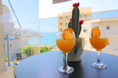 two glasses of orange juice on a table with a cactus at Ngjela Apartments in Sarandë