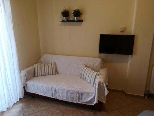 a living room with a white couch and a flat screen tv at Makis Nest Apart-Hotel in Vourvourou