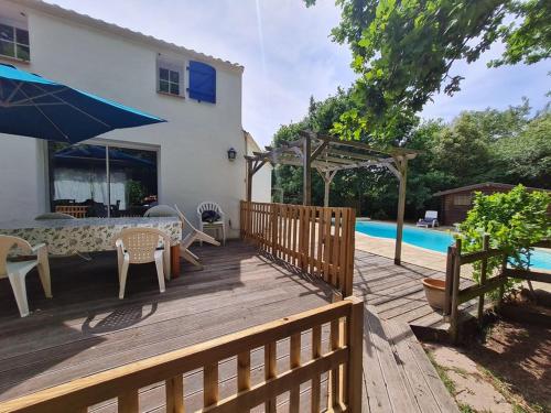 una terrazza in legno con tavolo e sedie accanto alla piscina di MAISON OROUET PISCINE 4 CHAMBRES a Saint-Jean-de-Monts