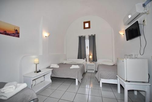 a white room with two beds and a television at Caldera View Resort - Adults Only in Akrotiri