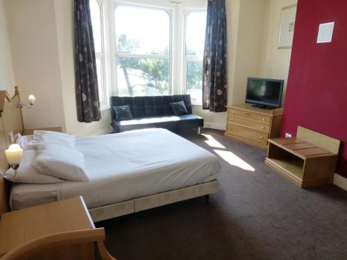 a bedroom with a bed and a couch and a television at Esplanade Hotel - Clacton On Sea, Beachfront Hotel by OYO in Clacton-on-Sea