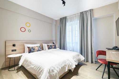 a bedroom with a bed and a desk and a window at The Mavili urban stay in Thessaloniki