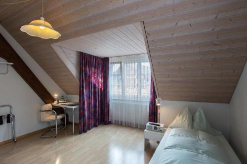 a bedroom with a bed and a desk in a attic at Seminarhotel Linde Stettlen in Bern