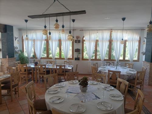 a dining room with tables and chairs and windows at Hotel Galera in Galera