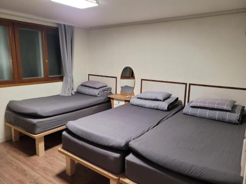 two twin beds in a room with a mirror at Able Guesthouse Hongdae 2 in Seoul