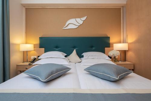 - un grand lit avec deux oreillers et une tête de lit verte dans l'établissement Aparthotel Flora, à Tučepi