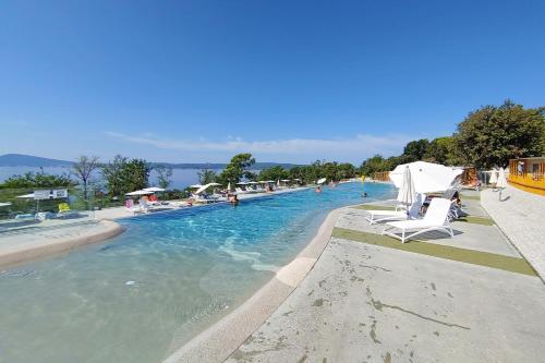 una piscina con sillas y gente en el agua en Luxury Mobile Houses Adria, en Selce