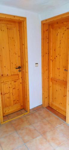 an empty room with two wooden doors and a tile floor at Casa Servatius in Briedel