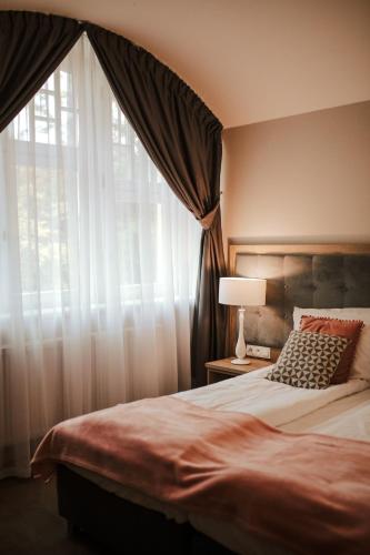 a bedroom with a bed and a window with curtains at Hotel Dębowy Biowellness & SPA Góry Sowie in Bielawa