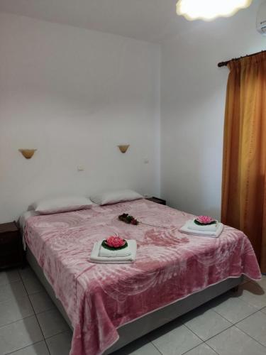 a bedroom with a bed with pink sheets and flowers on it at Ekaterini Apartments in Gouvia