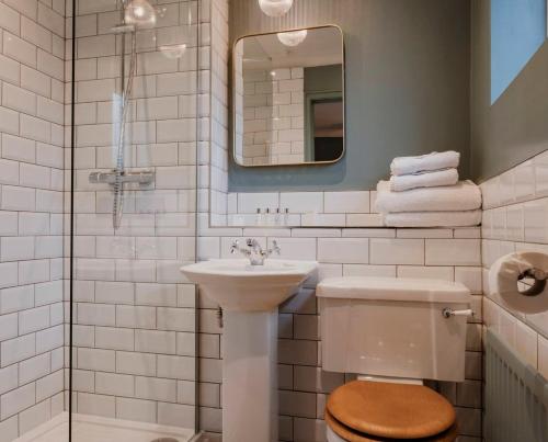 uma casa de banho com um lavatório, um WC e um espelho. em Fisherman's Haunt Hotel em Christchurch