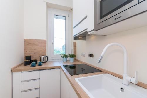 a kitchen with white cabinets and a sink and a window at Family Apartment in zona Lingotto by Wonderful Italy in Turin