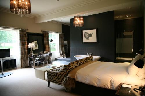 a bedroom with a bed and a tub and a desk at Milsoms Kesgrave Hall in Ipswich