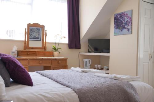 a bedroom with a bed and a tv and a window at The Eyre Court in Seaton