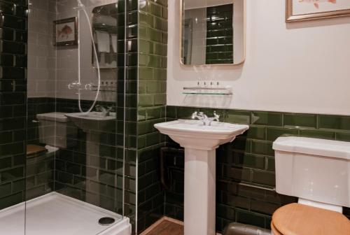 a green tiled bathroom with a sink and a toilet at Fisherman's Haunt Hotel in Winkton