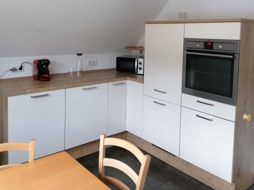 a kitchen with white cabinets and a microwave and a table at Ferienhaus Weitblick in Eslohe