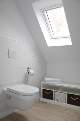 La salle de bains est pourvue de toilettes blanches et d'une lucarne. dans l'établissement Elske´s Stuuv, à Krummhörn
