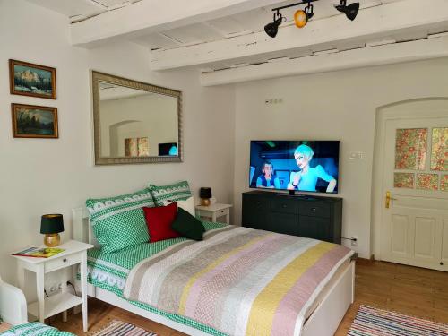 a bedroom with a bed and a flat screen tv at Vidéki vendégház Szögliget in Szögliget