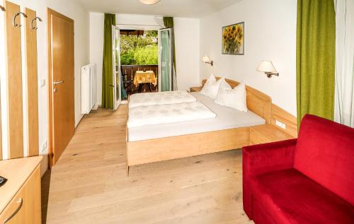um quarto com uma cama e uma cadeira vermelha em Ferienwohungen Gamper em Tirolo