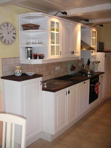 a kitchen with white cabinets and a clock on the wall at Blockstube in Rammenau
