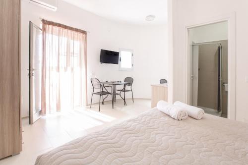 a white bedroom with a large bed and a table at Villa Coppitella, rooms & apartments in Vieste
