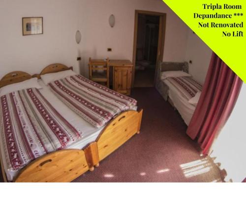 two twin beds in a room with a yellow picture at Alpen Resort Bivio in Livigno