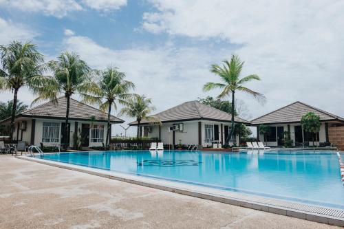 una gran piscina frente a las casas con palmeras en Comforta Hotel Tanjung Pinang, en Tanjung Pinang