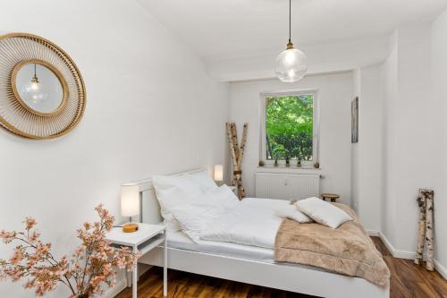 ein weißes Schlafzimmer mit einem Bett und einem Fenster in der Unterkunft City-Apartment direkt in den Parkanlagen in Bremen