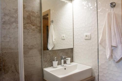 La salle de bains blanche est pourvue d'un lavabo et d'un miroir. dans l'établissement Apartman Joso, à Sukošan
