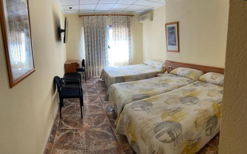 una habitación de hotel con 2 camas y una silla en Hostal Rosaleda, en Alcalá de Chivert