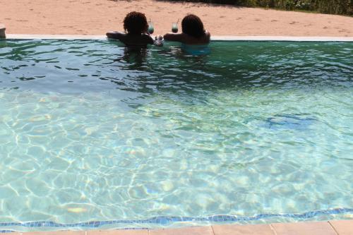 two women are sitting in a swimming pool at Lions Rock Rapids - Luxury Tented Camp in Hazyview
