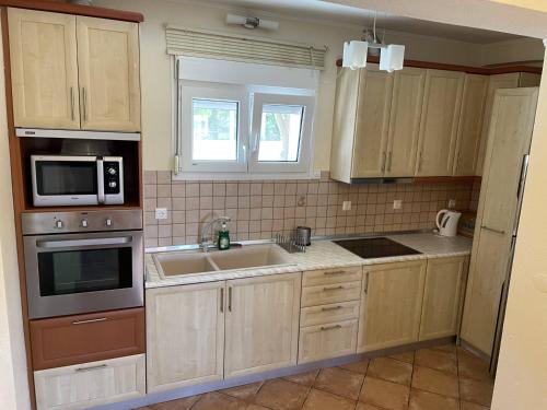 a kitchen with wooden cabinets and a sink and a microwave at Makis Nest Apart-Hotel in Vourvourou