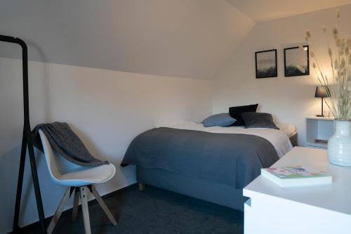 a bedroom with a bed and a chair and a desk at Weberhof Ferienapartments in Rostrup am Westufer des Zwischenahner Meers in Bad Zwischenahn