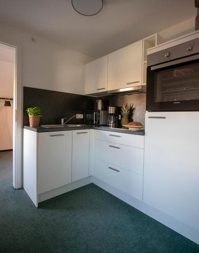 a kitchen with white cabinets and a stove top oven at Weberhof Ferienapartments in Rostrup am Westufer des Zwischenahner Meers in Bad Zwischenahn