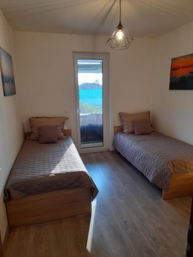 dwa łóżka w pokoju z oknem w obiekcie Sunset Beach Apartment direkt am Strand mit Pool Garten Terasse viel Komfort w Siófoku